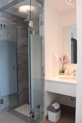 a bathroom with a glass shower and a sink at ResT Bangkok Poshtel in Bangkok