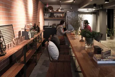 a group of people sitting at a long wooden bar at BED STATION Hostel Ratchthewi in Bangkok