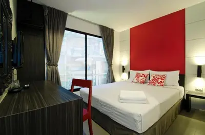 a bedroom with a large bed with a red wall at DI Place in Bangkok