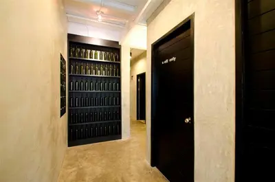 a hallway with black doors and racks of wine bottles at DI Place in Bangkok