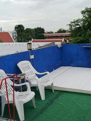 two white chairs and a bed on a roof at Sleep at home hostel in Bangkok