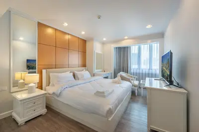 a bedroom with a large white bed and a television at Neom Town Residence in Bangkok