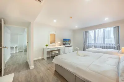 a white bedroom with a large bed and a desk at Neom Town Residence in Bangkok