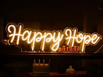 a neon sign that says happy hope on a window at Happy Hope in Bangkok
