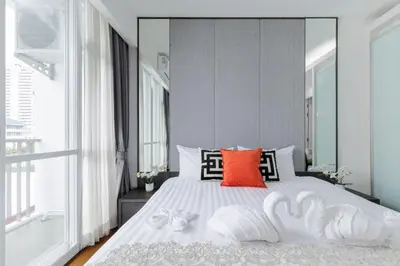 a bedroom with a white bed with a red pillow at Shine Sukhumvit 43 Apathotel Phrompong in Bangkok
