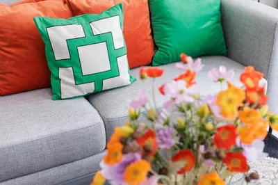 a couch with a pillow and flowers on a table at Shine Sukhumvit 43 Apathotel Phrompong in Bangkok