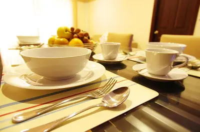 a wooden table with a bowl and plates and silverware at The Ninth Place Serviced Residence in Bangna