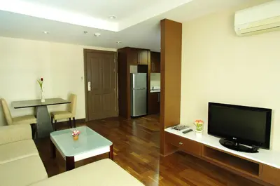 a living room with a couch and a tv and a table at The Ninth Place Serviced Residence in Bangna