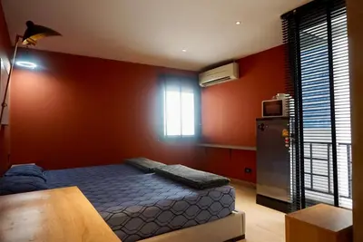 a bedroom with a bed and a refrigerator and a window at Hash Apartment Silom Soi 3 - hip and funky with rooftop view in Bangkok