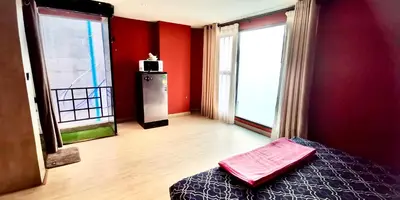a bedroom with red walls and a bed and two windows at Hash Apartment Silom Soi 3 - hip and funky with rooftop view in Bangkok
