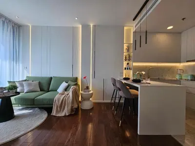 a living room with a green couch and a kitchen at The Address 28 in Bangkok