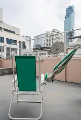 a green chair sitting on top of a balcony at Bangkok Dreamcatcher hostel in Bangkok