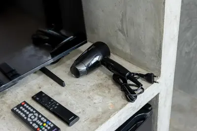 a hair dryer and two remote controls on a counter at Nature Boutique Residence in Bangkok