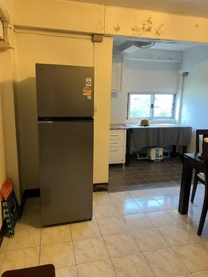 a kitchen with a refrigerator in the middle of a room at Mahasap Ramindhra next to MRT Station in Bang Khen