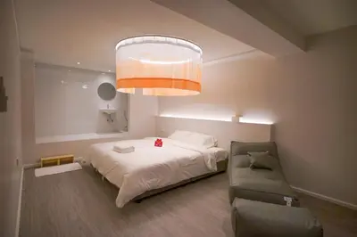 a bedroom with a bed and a couch and a chandelier at ABC Bangkok RCA in Bangkok