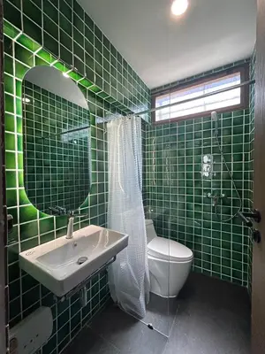 a green tiled bathroom with a sink and a toilet at Brown Brick Thonglor - Blue Blueberry Room in Khlong Toei