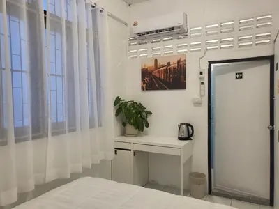 a bedroom with a bed and a desk and window at Aunty Thong's House in Bangkok