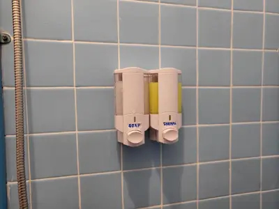 a bathroom with two soap dispensers on a tiled wall at Aunty Thong's House in Bangkok