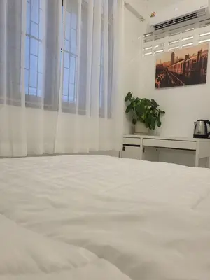 a bedroom with a large white bed with windows at Aunty Thong's House in Bangkok