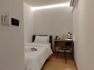 a bedroom with a bed and a desk with a chair at The Motuga Hostel Bangkok in Bangkok