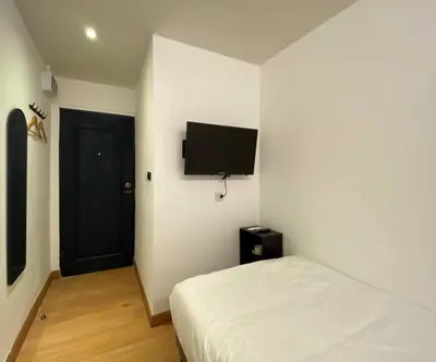 a bedroom with a bed and a flat screen tv on the wall at The Motuga Hostel Bangkok in Bangkok