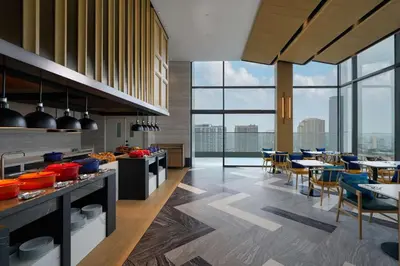 a kitchen and dining room with tables and chairs at Hilton Garden Inn Bangkok Riverside in Bangkok
