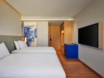 a hotel room with two beds and a flat screen tv at Hilton Garden Inn Bangkok Riverside in Bangkok
