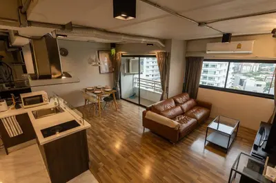 a living room with a leather couch and a kitchen at Cozy 2BR Duplex-Apartment in Thong Lor in Bangkok