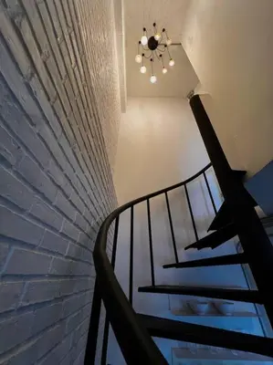 a staircase with a brick wall and a chandelier at Cozy 2BR Duplex-Apartment in Thong Lor in Bangkok