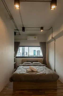 a bedroom with a large bed with a window at Cozy 2BR Duplex-Apartment in Thong Lor in Bangkok