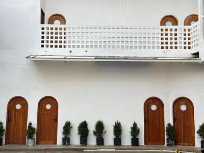 a white building with wooden doors and potted plants at Megun 10 in Ban Bang Phlat