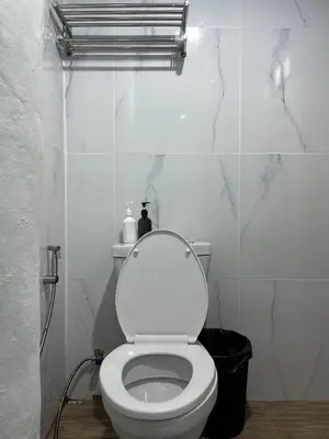 a white bathroom with a toilet with the lid up at Megun 10 in Ban Bang Phlat