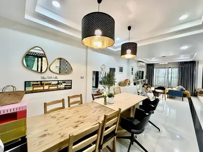 a dining room and living room with a wooden table and chairs at Homemii 59 in Ban Chuat Plai Mai