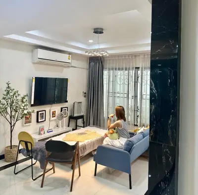 a woman sitting on a couch in a living room at Homemii 59 in Ban Chuat Plai Mai