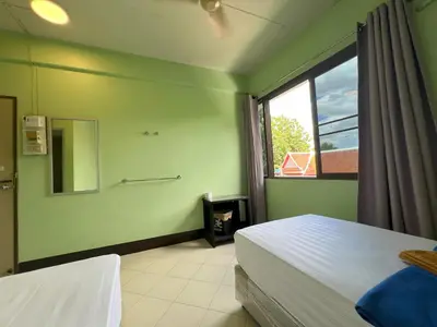 a green room with two beds and a window at Bella Bella House in Bangkok