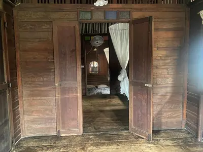 an open wooden door in a room with a bed at Chest's Place in Bangkok