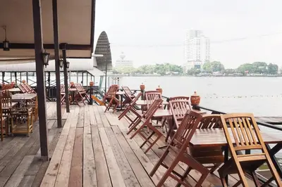 a row of tables and chairs on a dock with the water at Kaloang home in Bangkok