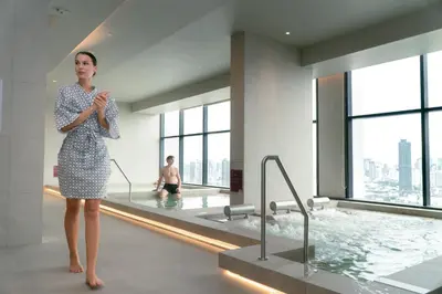 a woman standing in a bathroom with a swimming pool at Cassia Rama 9 Bangkok, part of Banyan Group in Bangkok