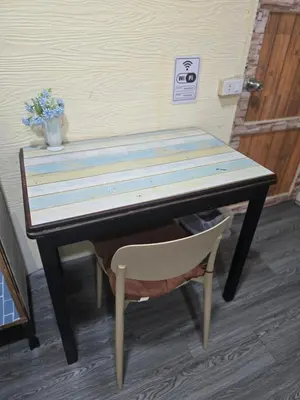 a wooden table with a chair and a vase of flowers at 204 Olan Place Spacious Studio with Wi-fi near BTS Skytrain in Bangkok