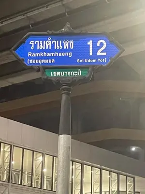 a blue street sign on a pole in a building at Le Ram Hotel No windows in Bangkok