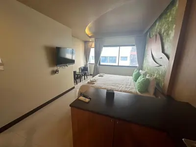 a bedroom with a bed with a desk and a tv at Le Ram Hotel No windows in Bangkok