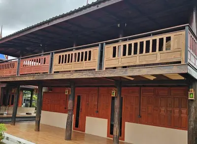 a train on top of a building with wooden doors at Nipatra Homestay in Ban Khlong Bang Sai