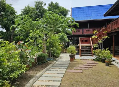 a garden with stepping stones in front of a building at Nipatra Homestay in Ban Khlong Bang Sai