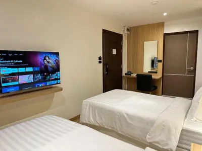 a hotel room with two beds and a flat screen tv at Winston Hotel in Bangkok