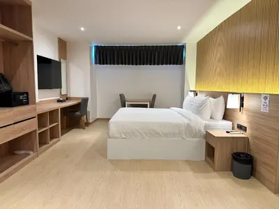 a hotel room with a bed and a desk and a tv at Winston Hotel in Bangkok