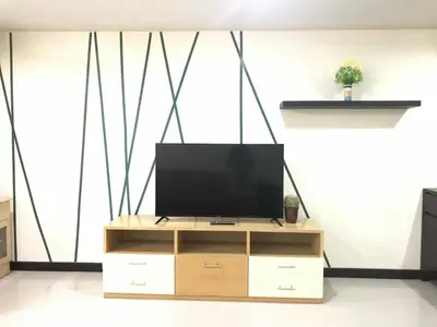 a television on a wooden entertainment center in a living room at Charming Resident Sukhumvit 22 in Bangkok