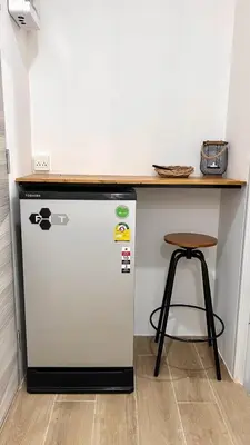a counter top over a refrigerator next to a table at 65 Hostel Bangkok in Bangkok Noi