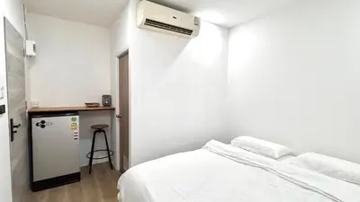 a white bedroom with a bed and a heater at 65 Hostel Bangkok in Bangkok Noi