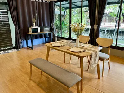 a dining room table with chairs and a table with flowers on it at Kirin Riverside Homestay with AC, WiFi in Bangkok in Rat Burana