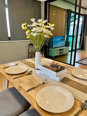a table with plates and a vase of flowers on it at Kirin Riverside Homestay with AC, WiFi in Bangkok in Rat Burana